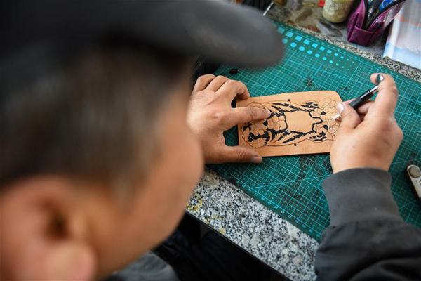        4月15日，在锡尼河镇的出租房内，米格木尔在皮制品上雕刻花纹。 新华社记者 刘磊 摄