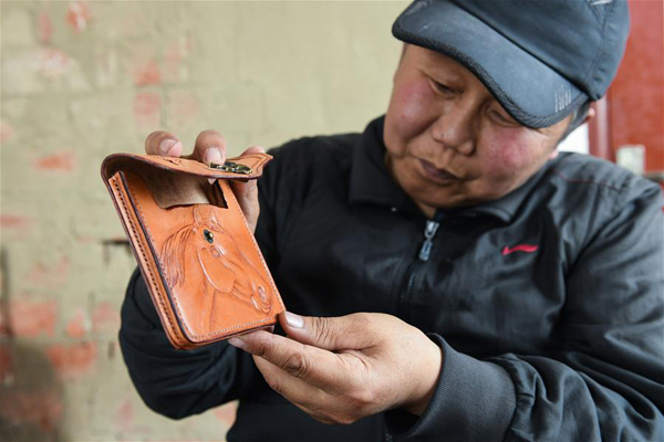        4月15日，在锡尼河镇的出租房内，米格木尔展示他培训结束后做的第一件皮雕制品。新华社记者 刘磊 摄