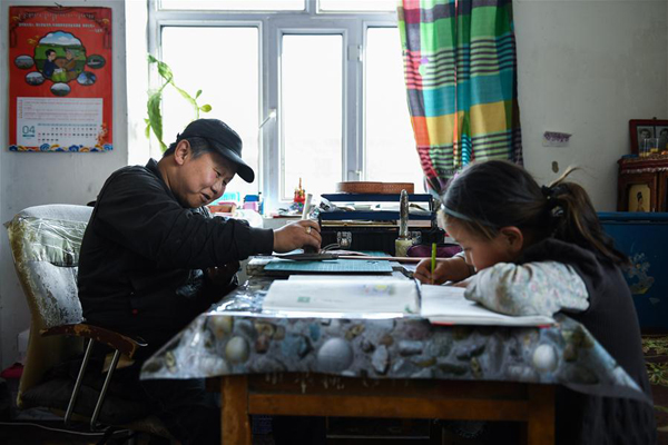        4月15日，在锡尼河镇的出租房内，米格木尔在进行皮雕，女儿南吉乐玛在温习功课。新华社记者 刘磊 摄