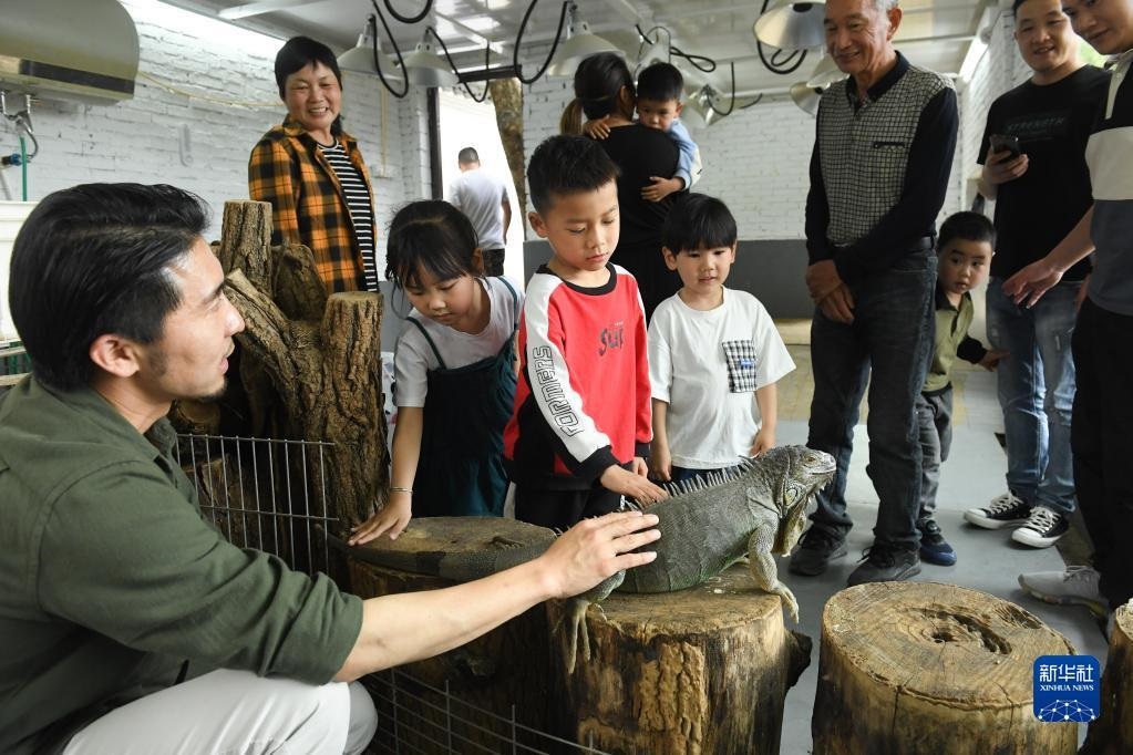 5月18日，保护中心的创立者田力（左一）给前来研学的家长和孩子介绍蜥蜴。

新华社记者 翁忻旸 摄